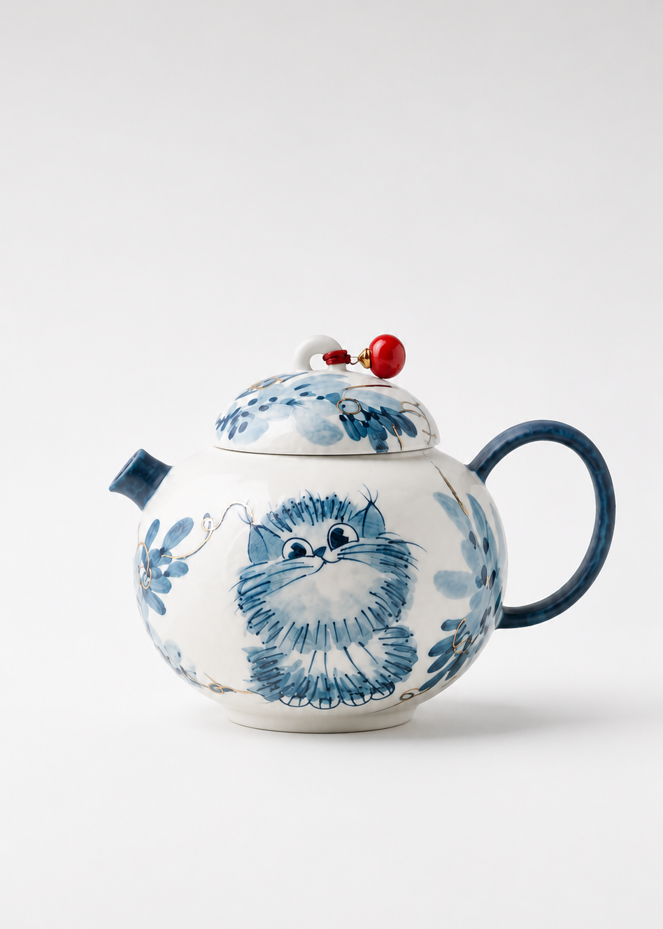 A white ceramic teapot decorated with a blue hand-painted style illustration of a fluffy creature, featuring a dark blue handle, spout, and lid knob, and a small red accent on top.