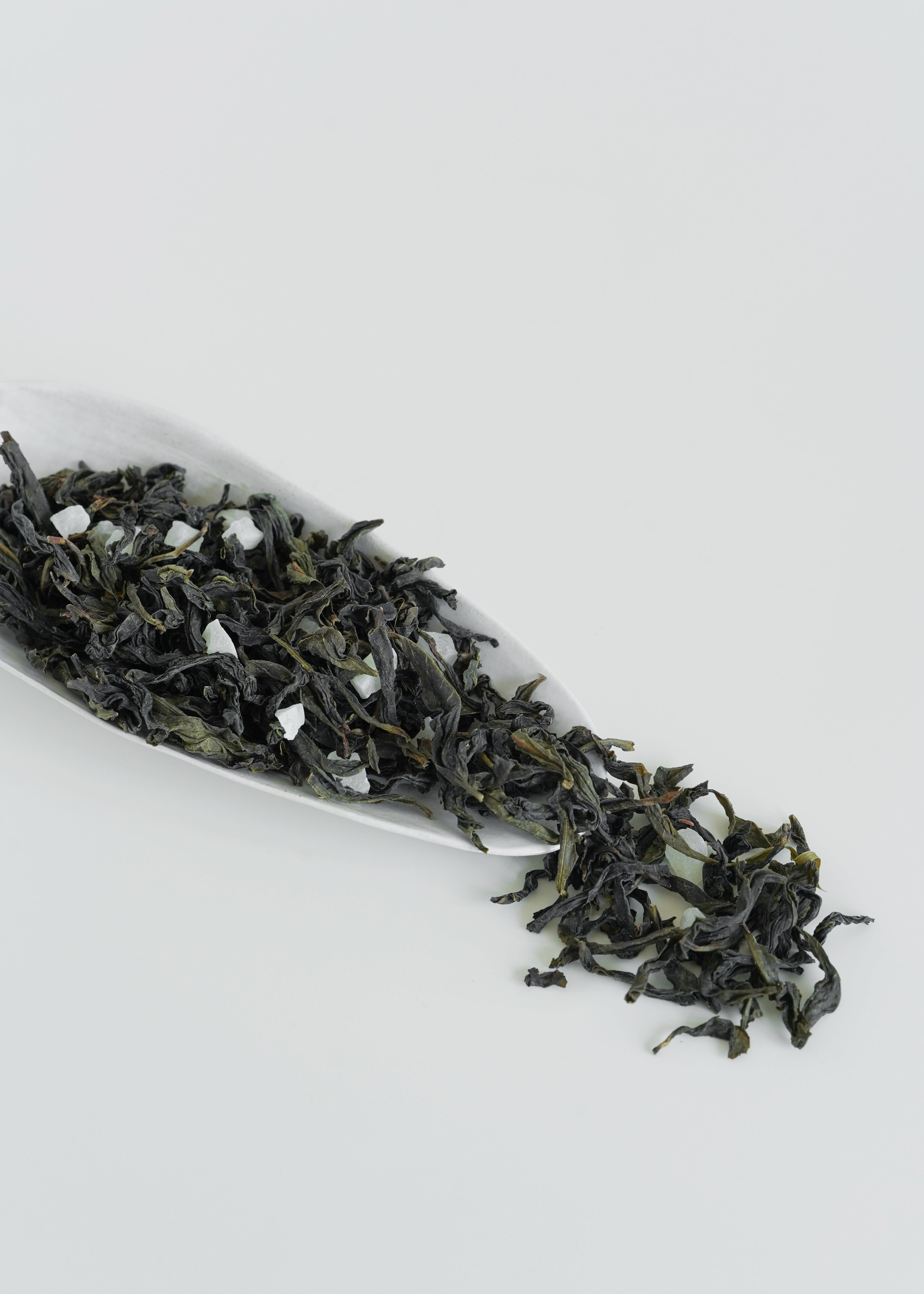 Dried green oolong tea leaves on a white background. Peach Oolong