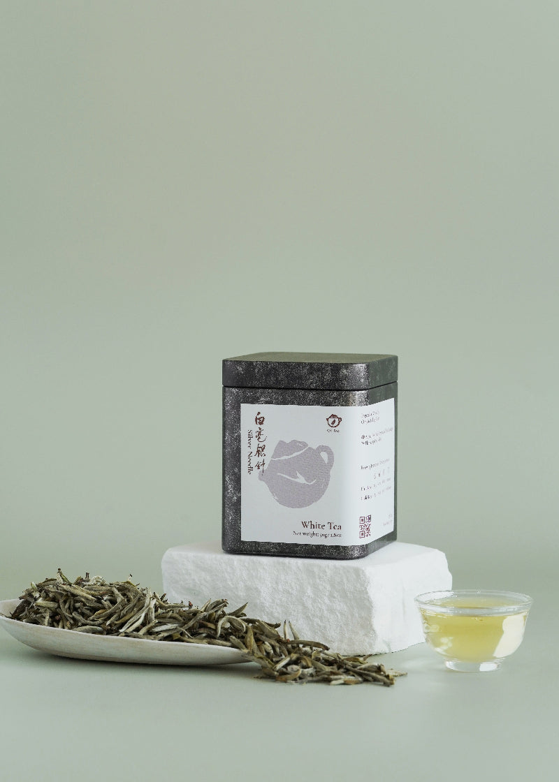 Tea packaging with tea leaves and a cup of tea on a light green background. Silver needle