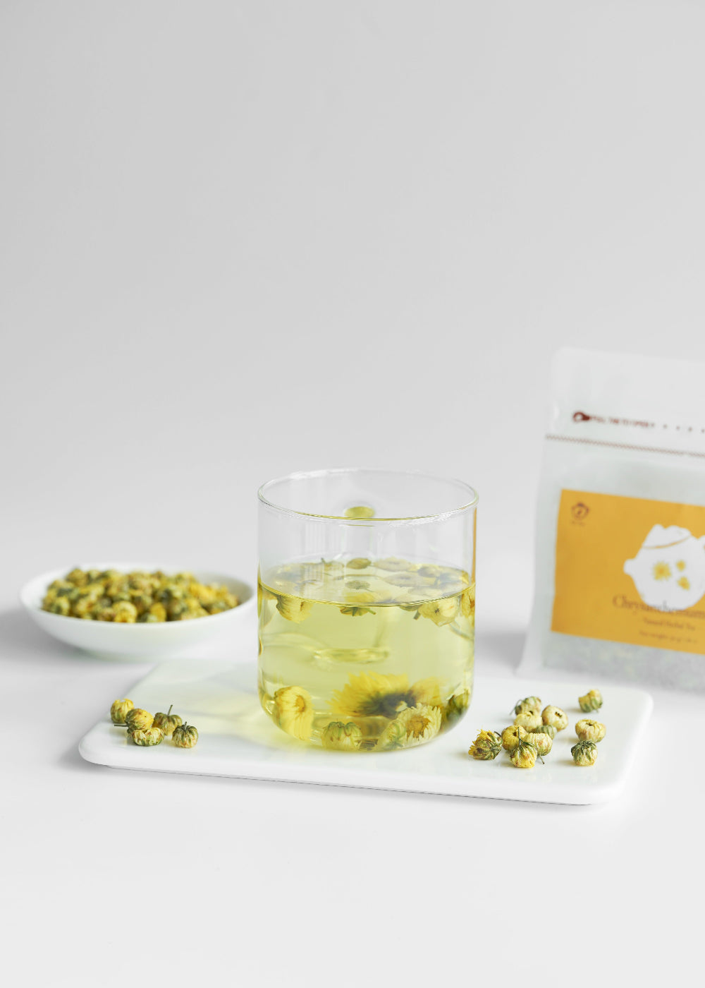 Glass of green tea with tea leaves on a white surface