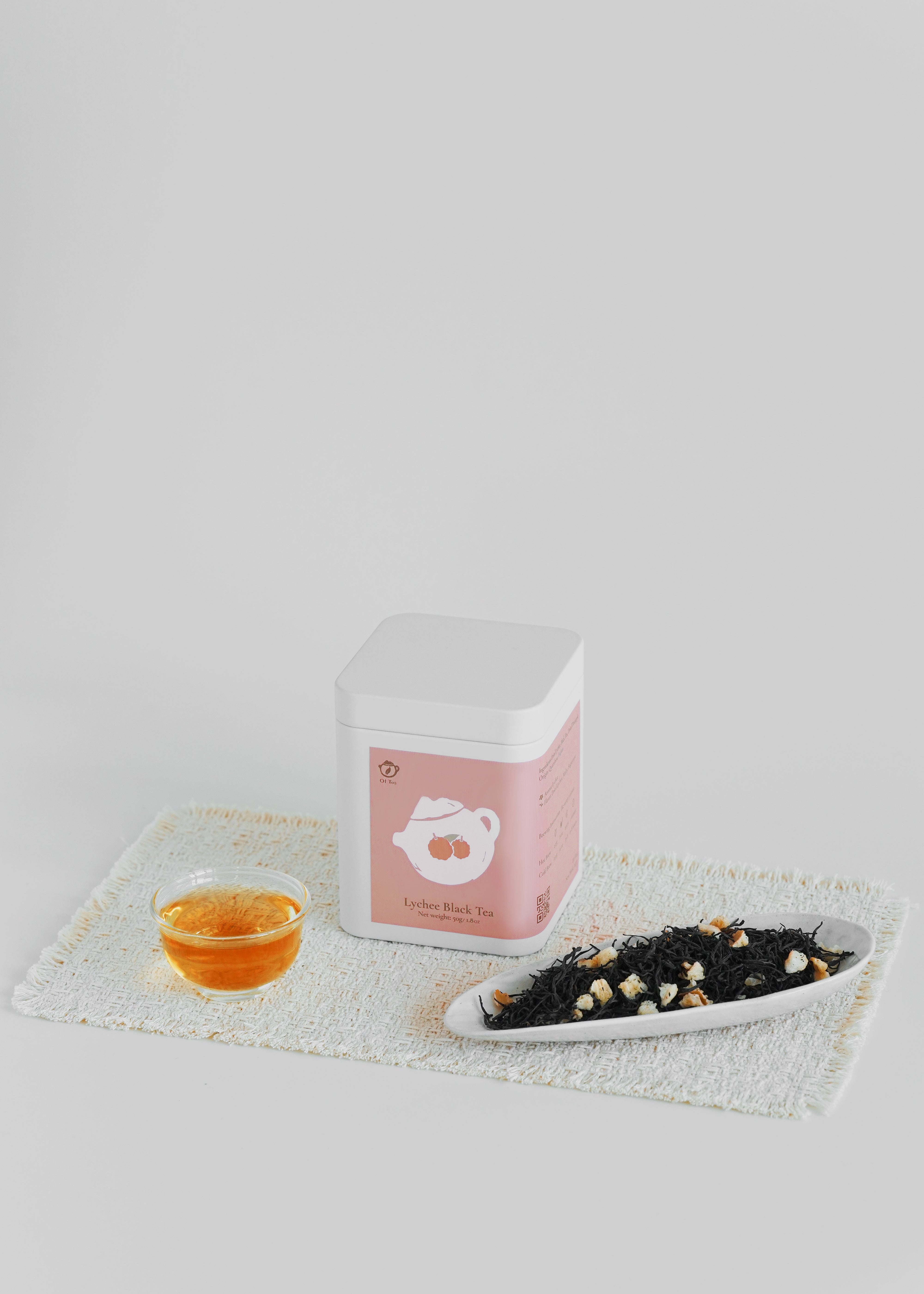 Tea packaging with a cup of tea and a plate of black tea leaves on a white background. Lychee black tea