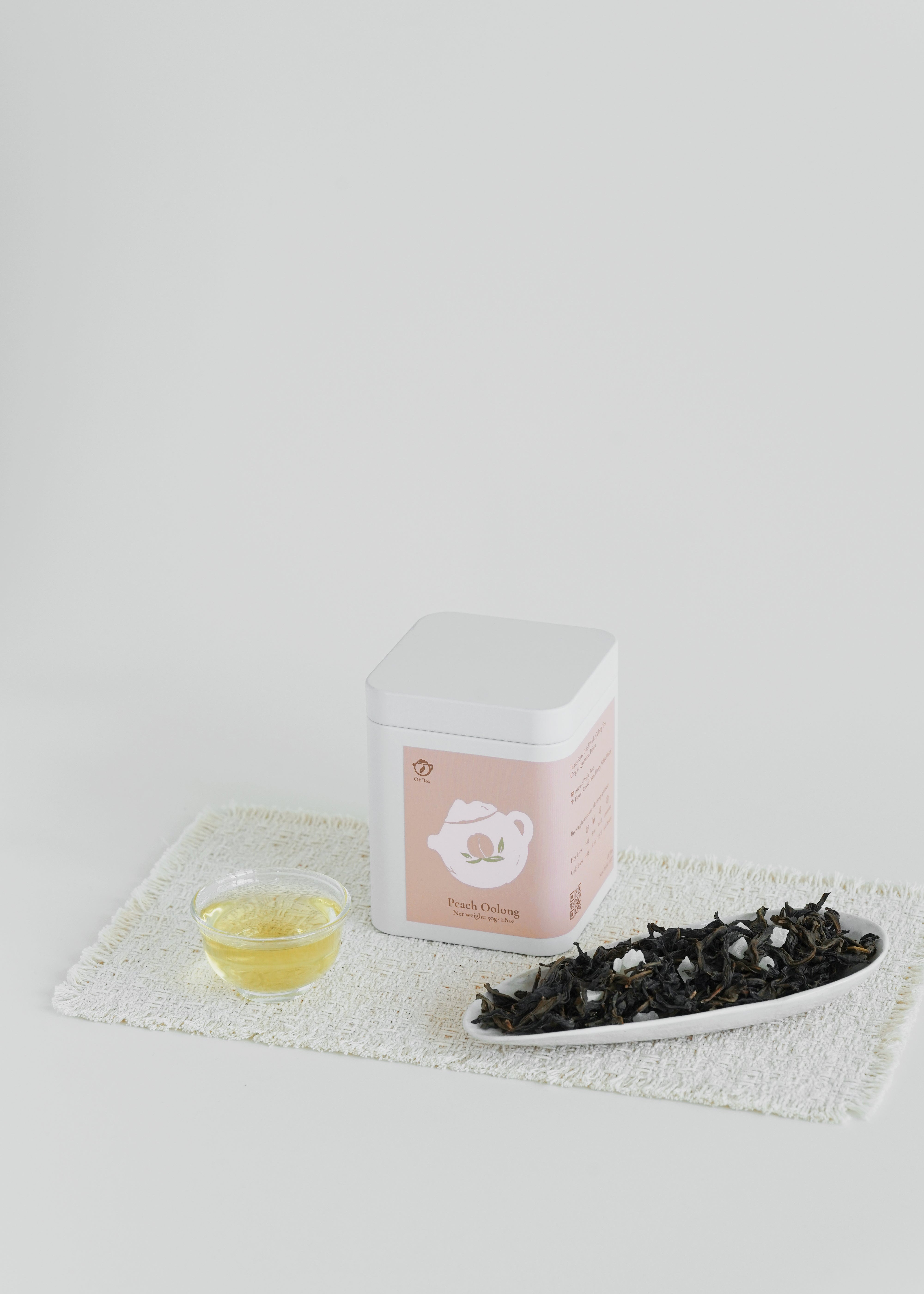 Tea packaging with a small bowl of liquid and a plate of tea leaves on a white background.  Peach Oolong