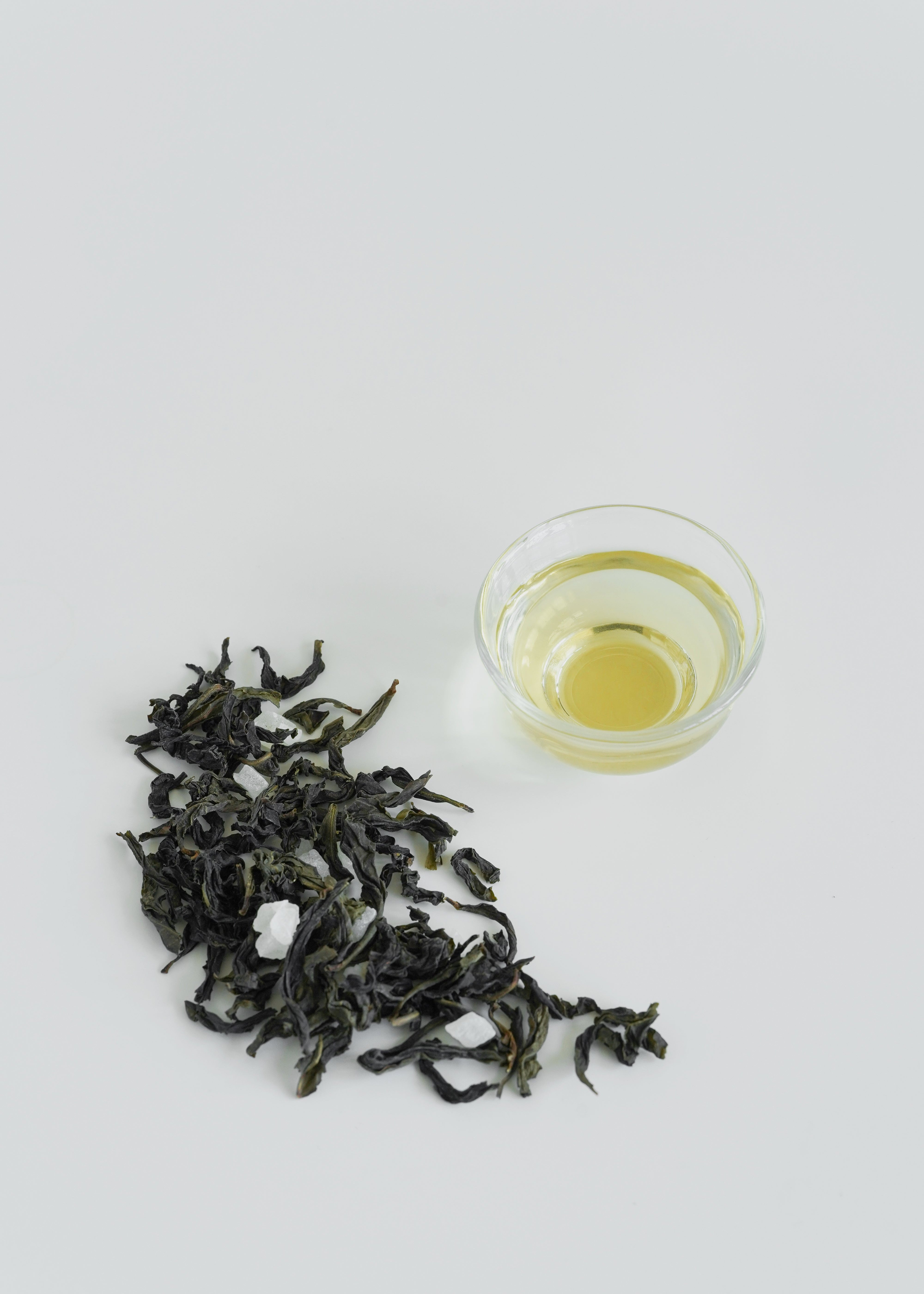 Dry green tea leaves and a glass of brewed tea on a white background. Peach Oolong