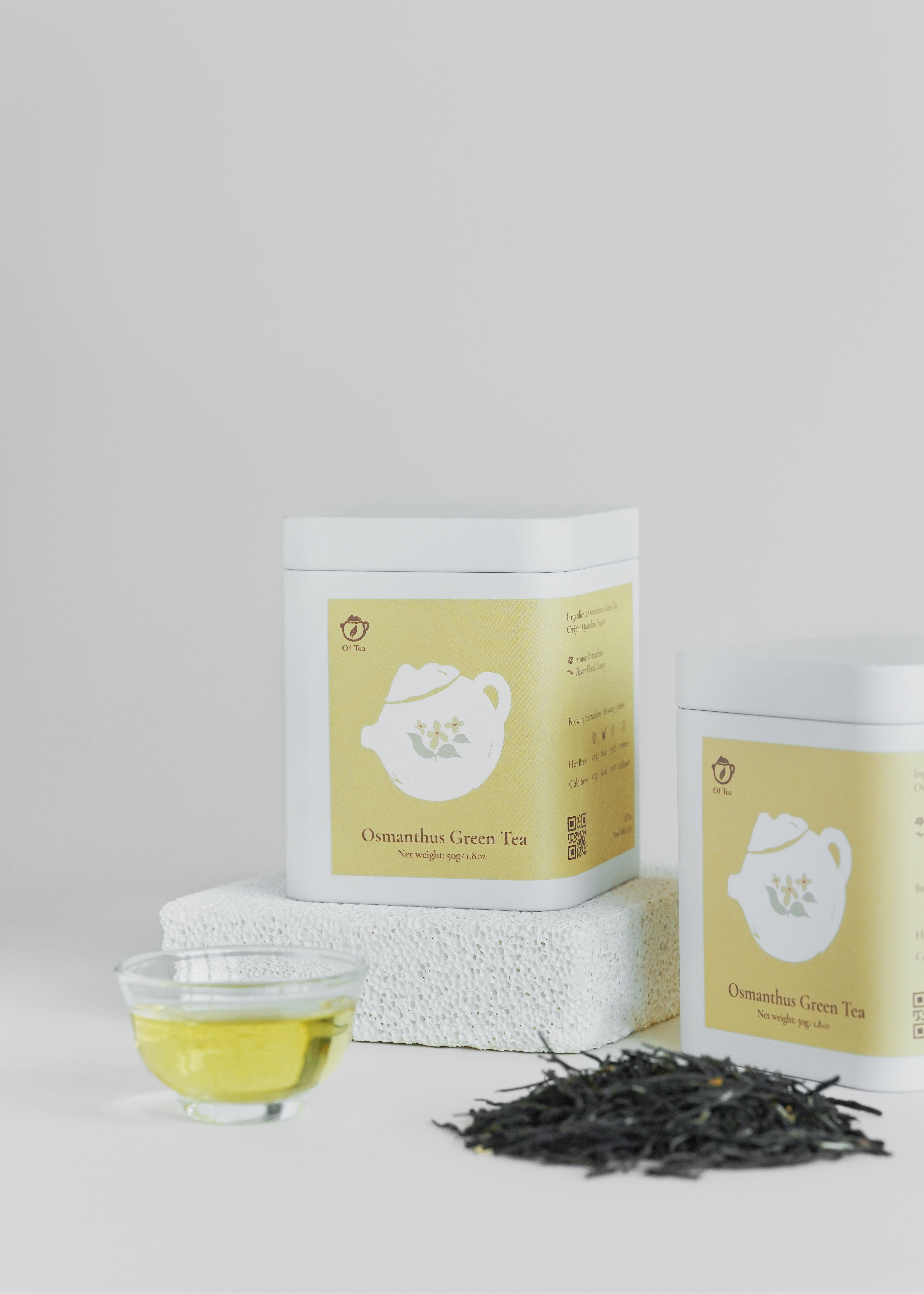 Tea packaging with a glass of tea and tea leaves on a light gray background