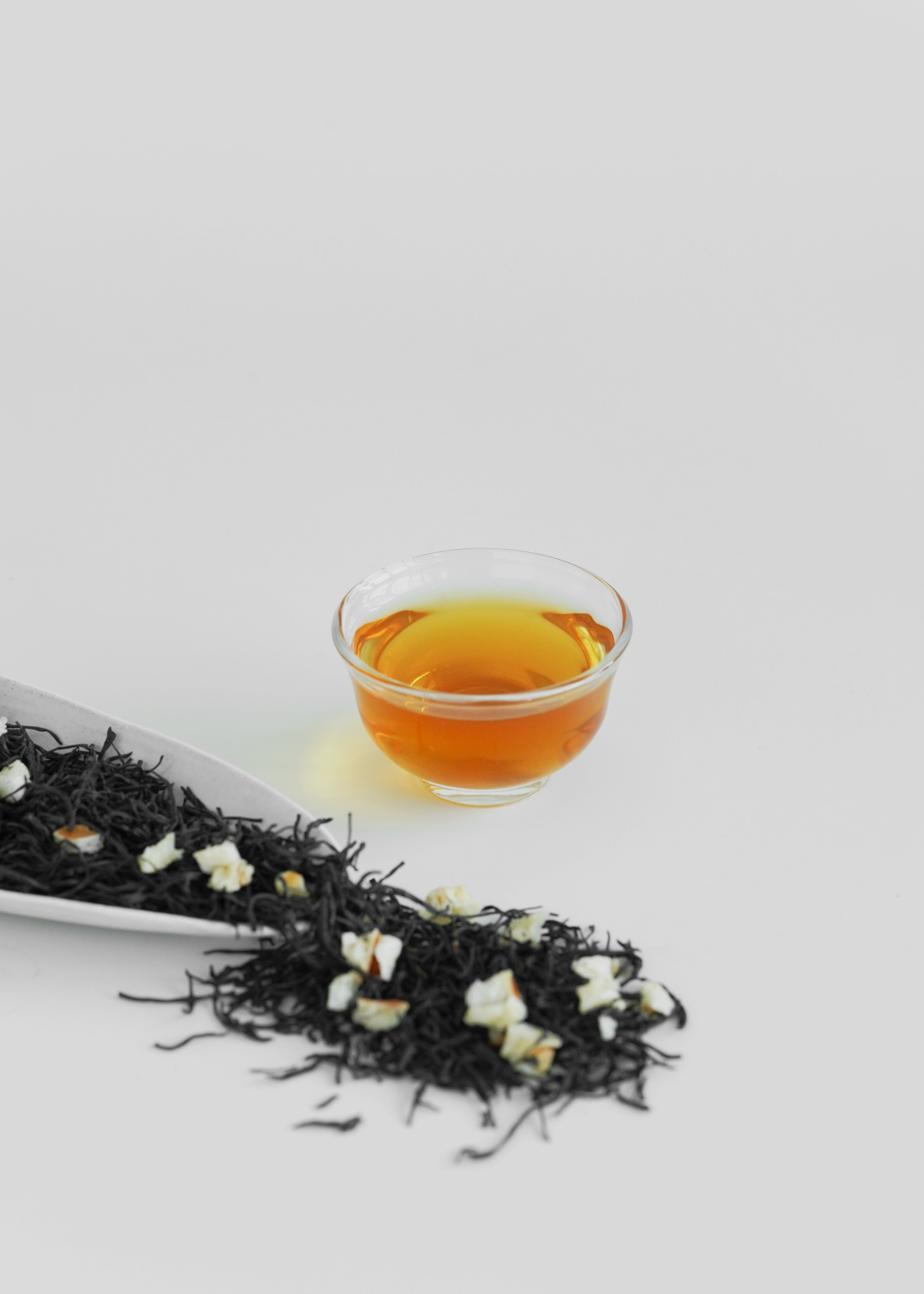 Tea leaves and a cup of tea on a light gray background. Lychee black tea