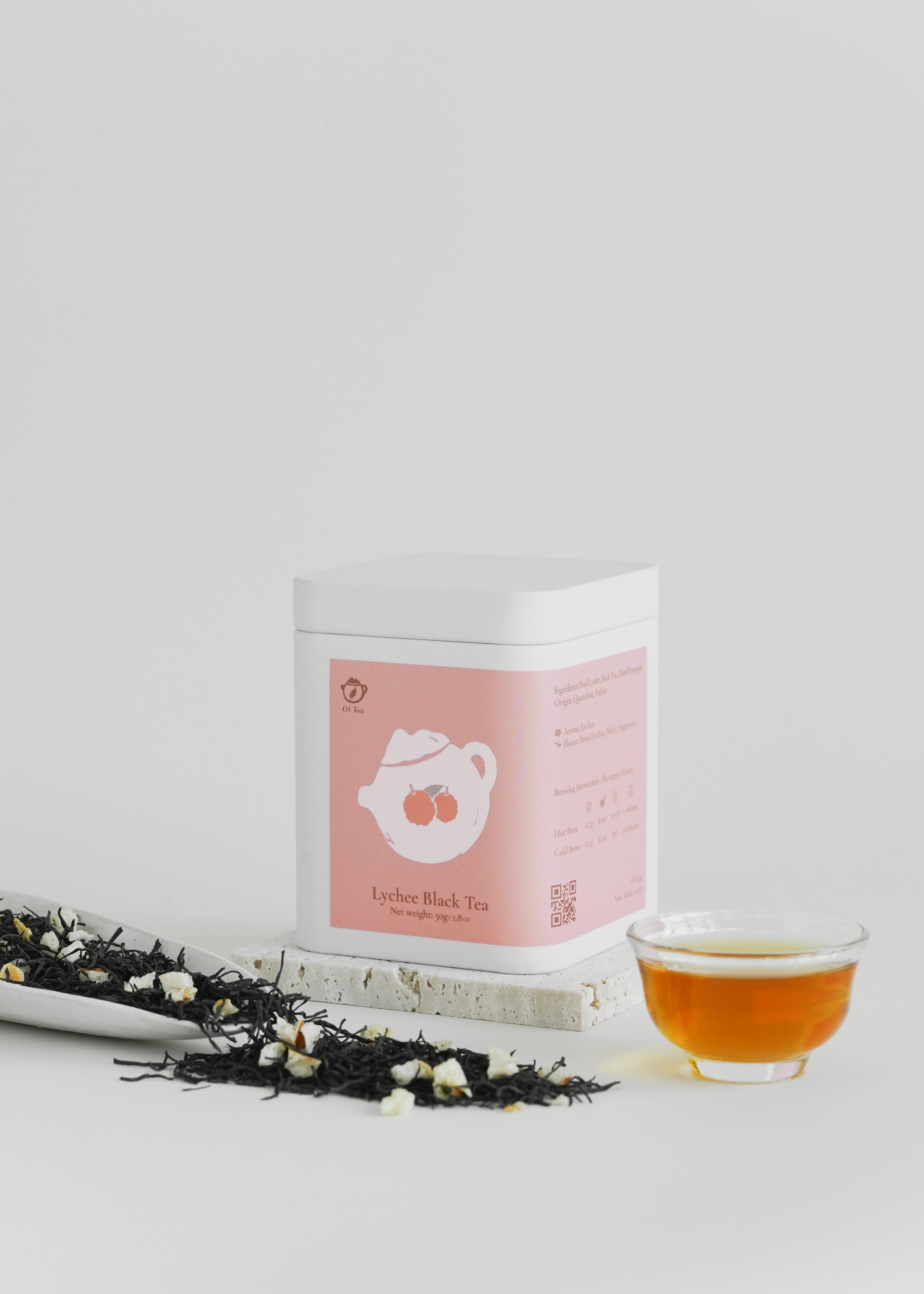Tea packaging with a cup of tea and loose tea leaves on a light gray background. Lychee black tea