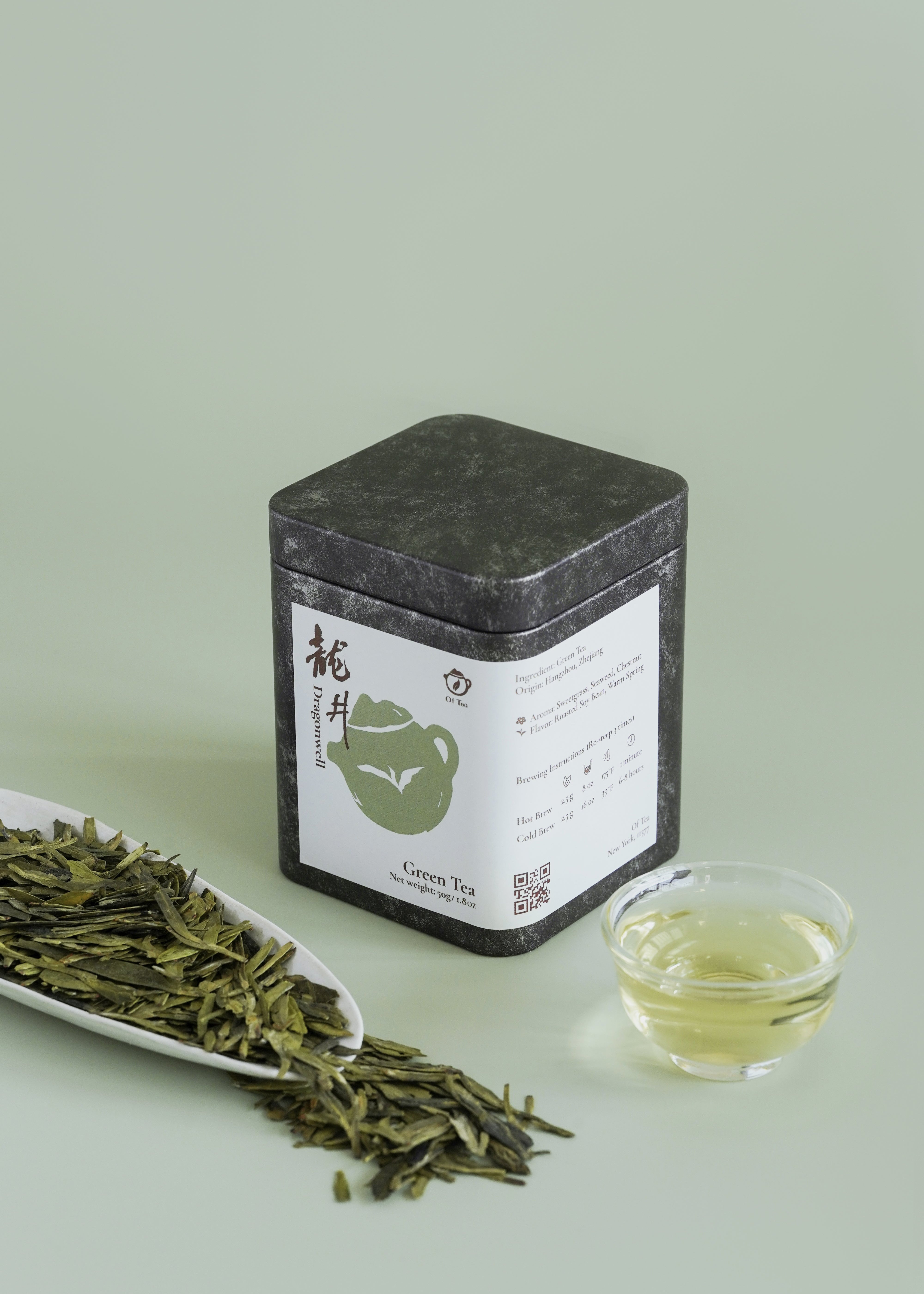 Tea canister with green tea leaves, a small cup of tea, and a scoop on a light green background. Dragon Well
