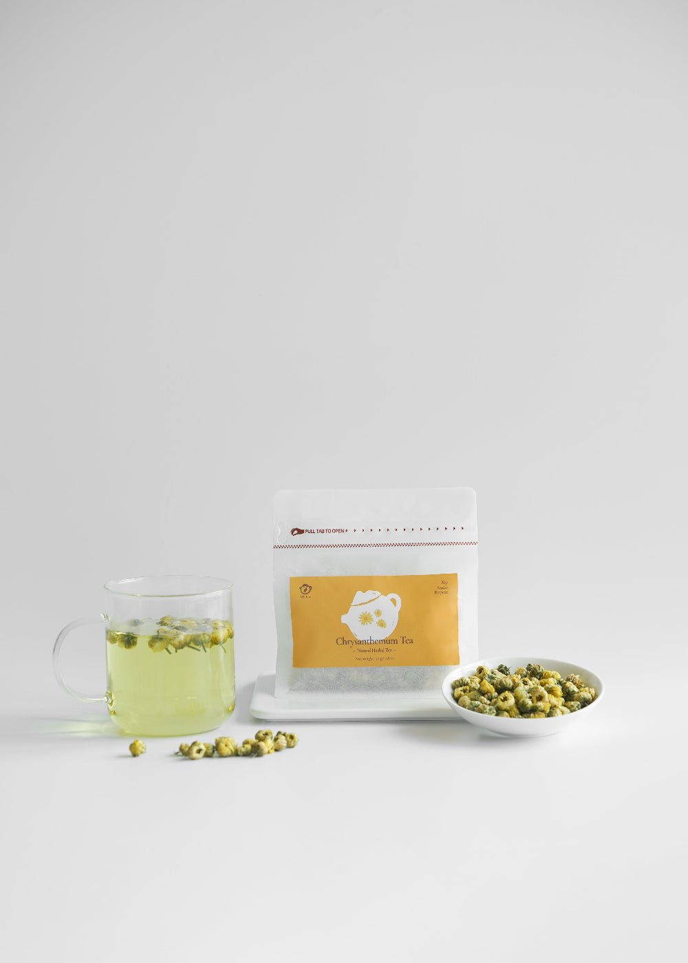 Tea bag, glass of tea, and bowl of tea leaves on a white background