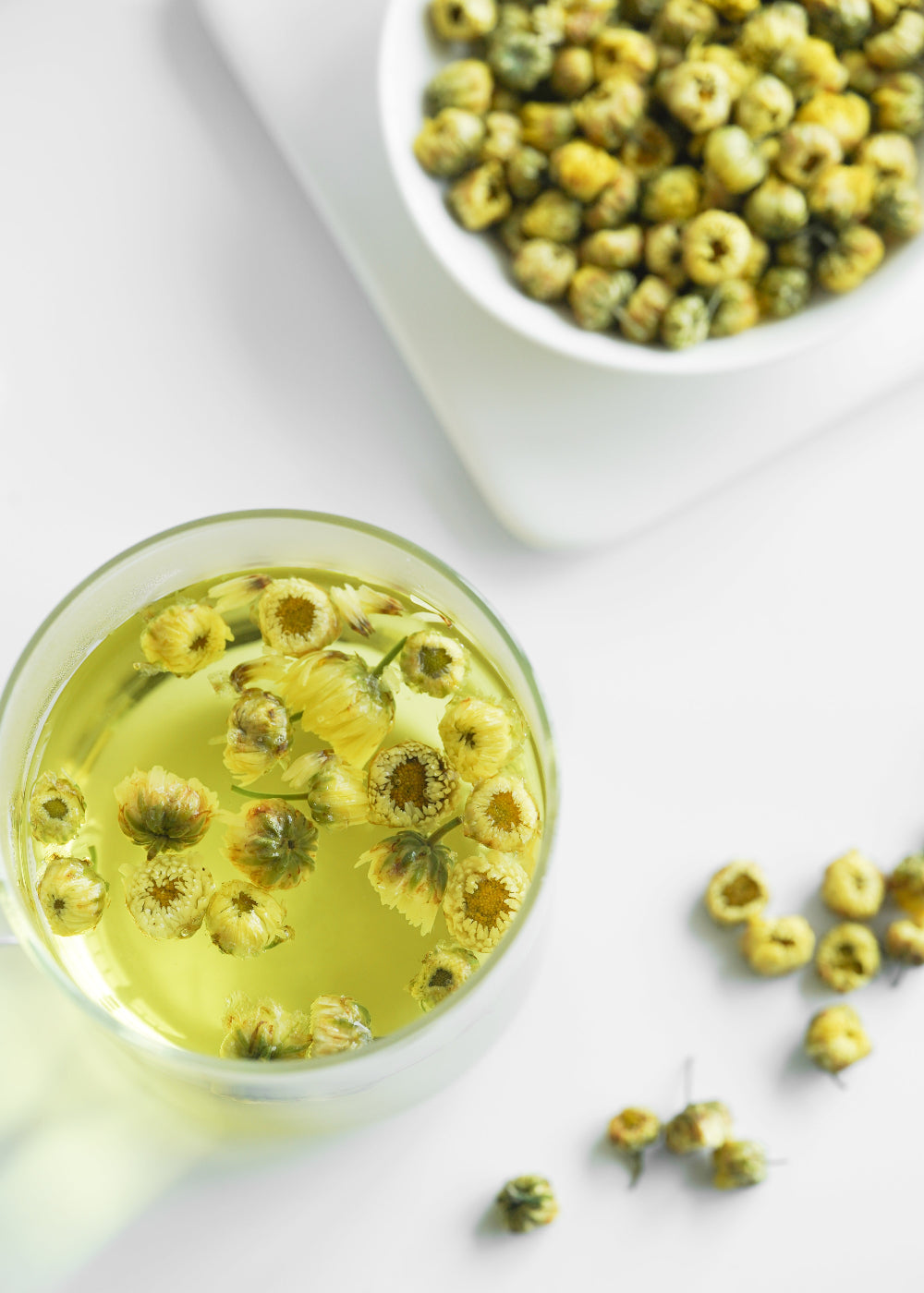 Glass of herbal tea with dried herbs on a white background