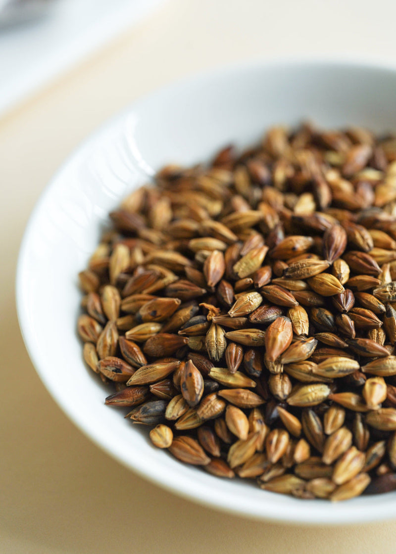White bowl filled with roasted seeds on a light wooden surface